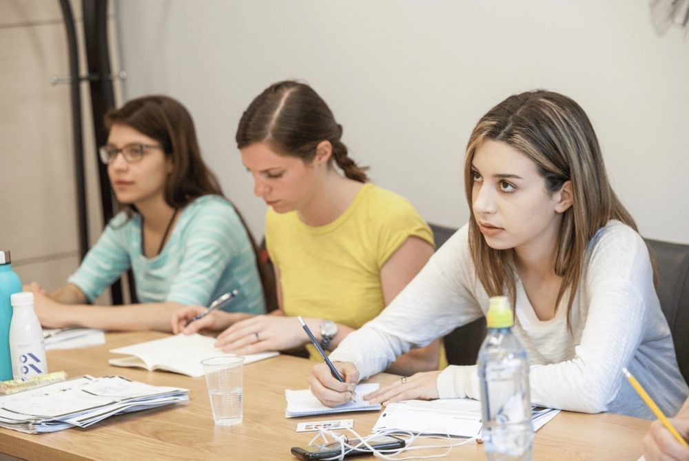 Three students taking notes in class